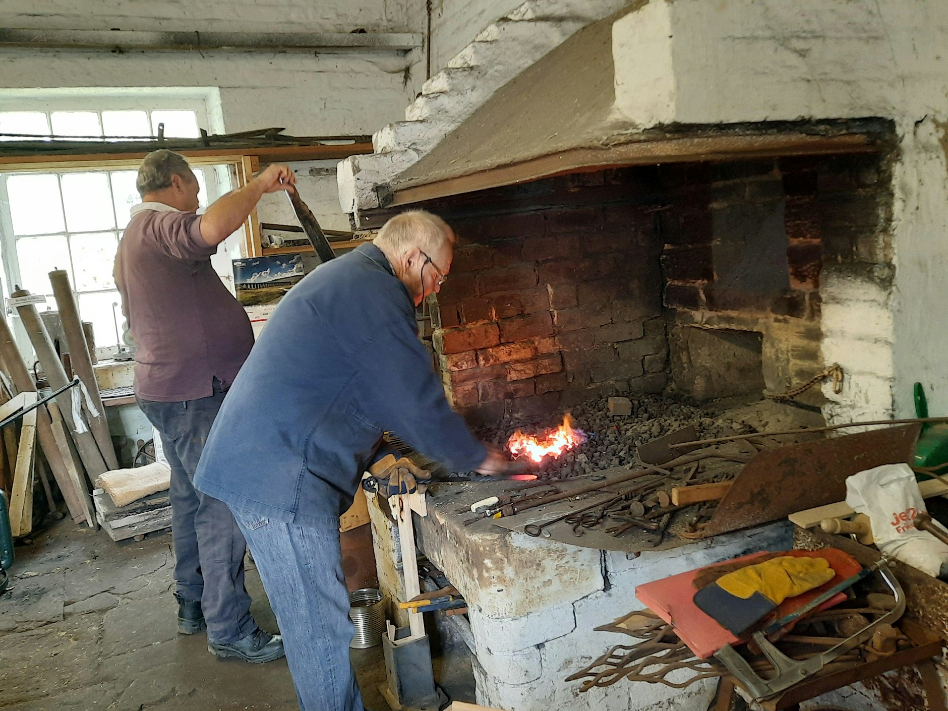 Two blacksmiths working in a forge