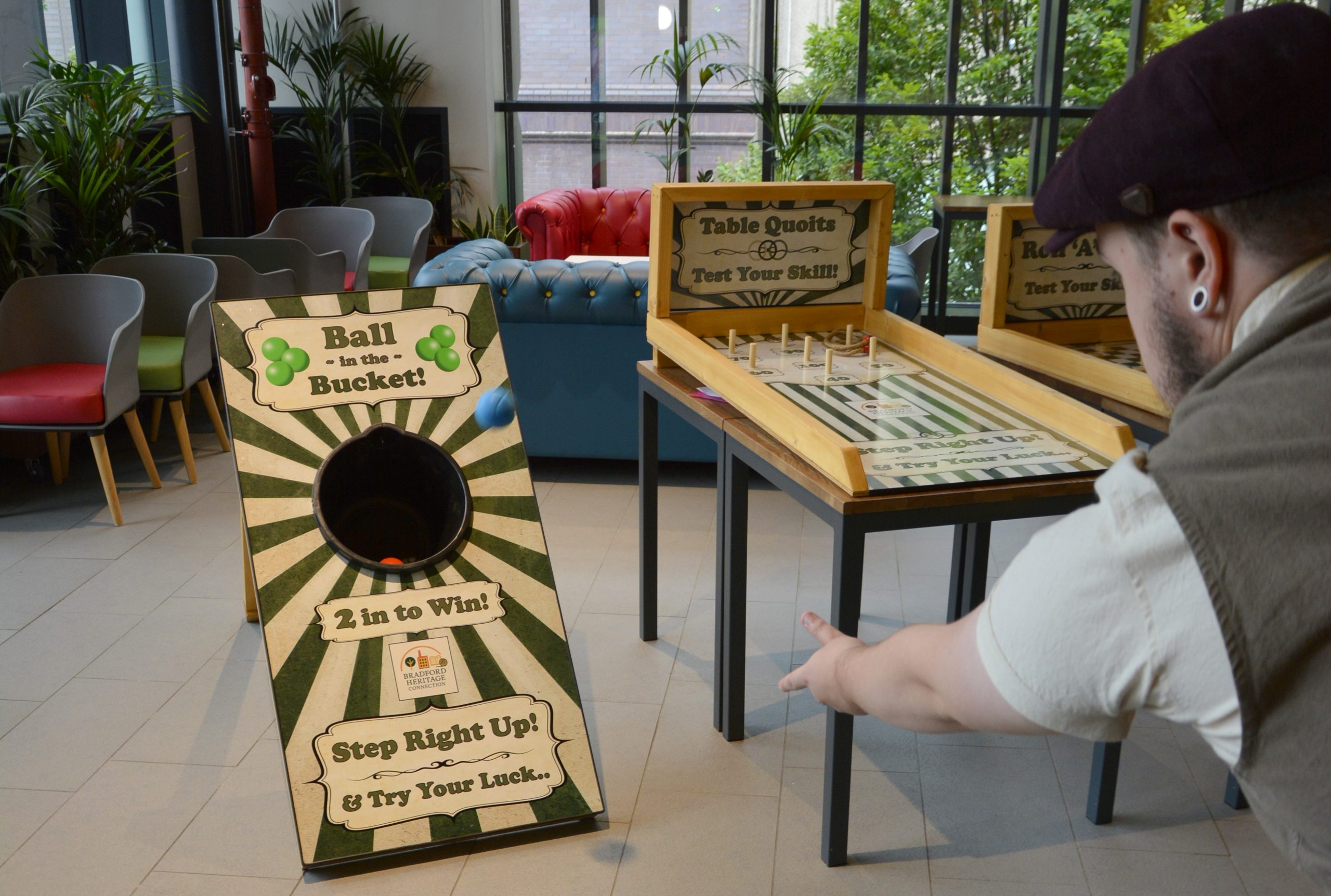 Image shows a man dressed in Victorian clothes throwing a ball into a carnival style game