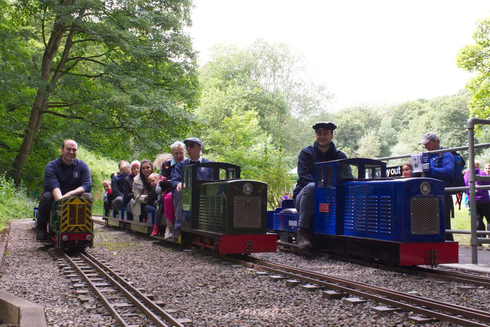 A group of people taking a ride on a minature railway through the woods