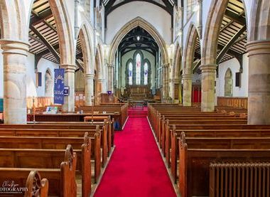 Interior of church with wooden pews, stone arches and red carpet