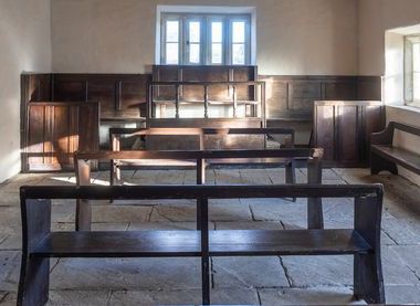 Room with rows od benches, stone flooring and wooden panelling